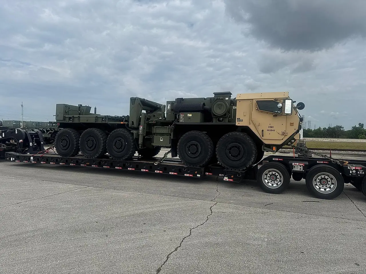 Multi-axle heavy vehicle secured on a lowboy trailer, viewed from the side
