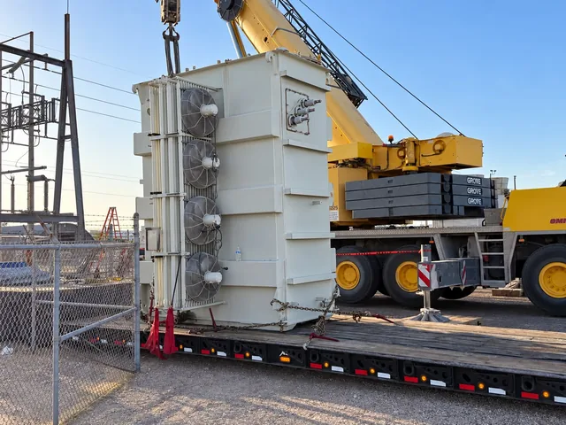 Large transformer being positioned on a trailer with a crane at an electrical site